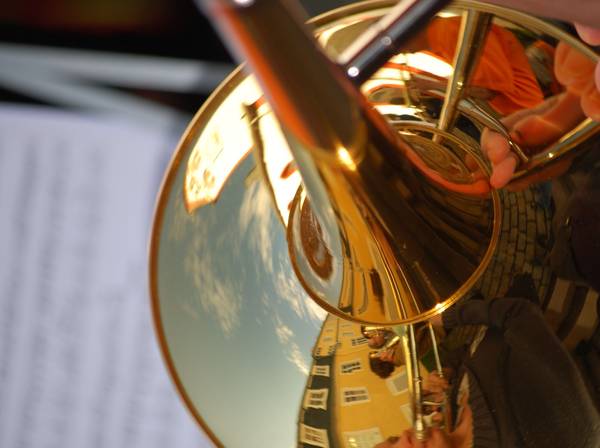 Posaunenchor mit einem sich in der Trompete spiegelnden Kirchturm.